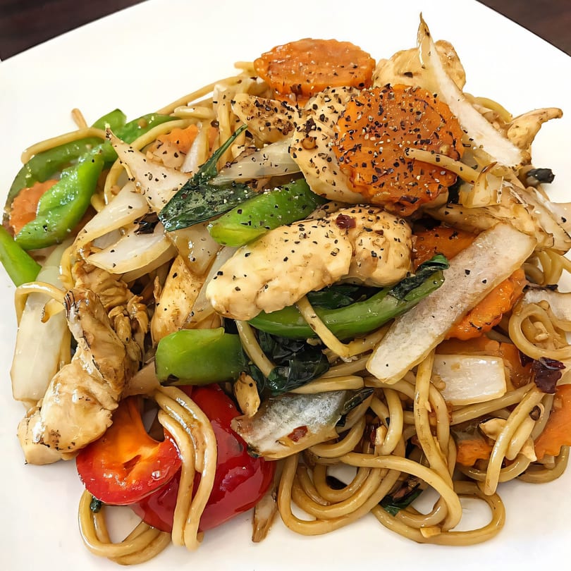 Close-up of Bangkok Corner's Thai noodles with chicken, bell peppers, carrots, and onions.